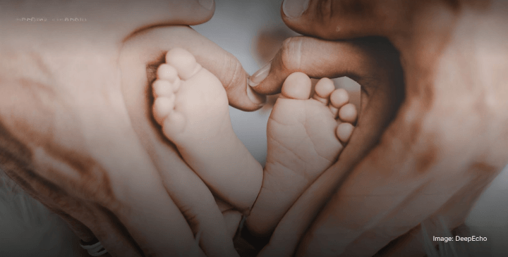 Adult hands form a heart shape around the tiny feet of a baby, symbolising anticipatory love and care for the child's future.