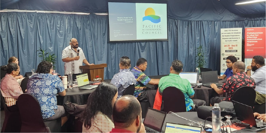 A man speaks at a lectern to a group seated at tables with laptops during a Pacific International Council meeting.