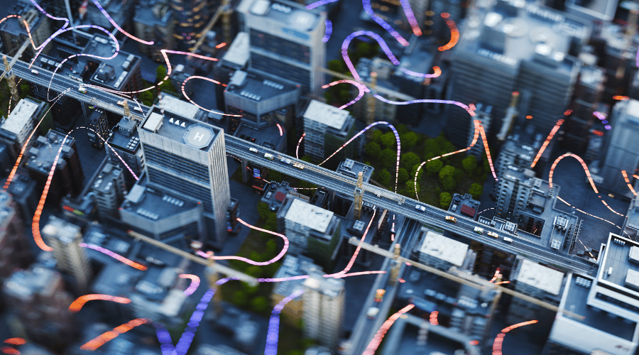 Aerial view of a modern city with tall buildings, a main road running through the centre, green patches of trees, and colourful abstract lines and streaks of light swirling above the cityscape. The image appears digitally enhanced.