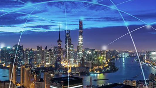 Night cityscape with illuminated skyscrapers and digital blue connectivity lines arcing over the skyline.