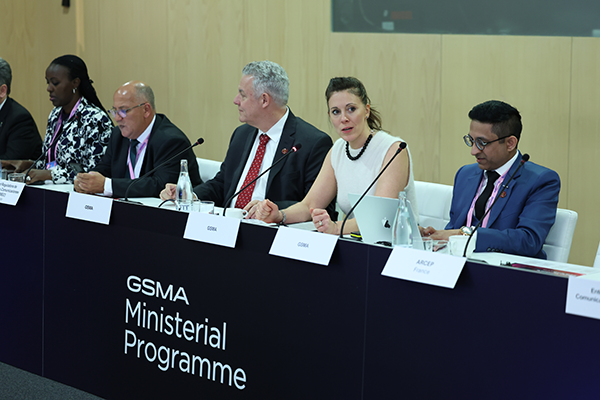Five people sit at a GSMA Ministerial Programme panel, speaking and listening, with nameplates in front of them.
