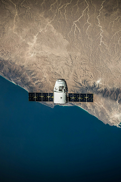 A satellite operates above a coastline, with land and ocean visible below, capturing data that supports effective satellite policy decisions.