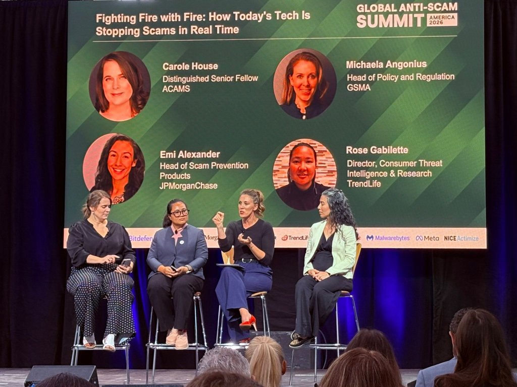 Five women sit on stage during a panel discussion at the Global Anti-Scam Summit. Behind them is a screen with headshots, names, and titles of four panelists. They discuss “Fighting Fire with Fire: How Today’s Tech Is Stopping Scams in Real Time.”.