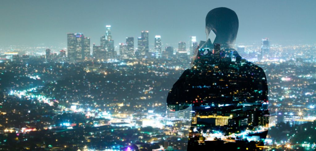 A silhouette of a person talking on a phone is superimposed over a brightly lit city skyline at night, with vibrant colors blending through the figure—symbolizing seamless connection enabled by 5G network-as-a-service NaaS API open-gateway.