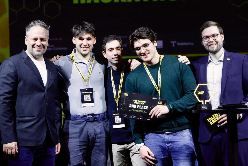 Five men stand together at an award event, with two holding a "2nd Place" certificate and trophy.