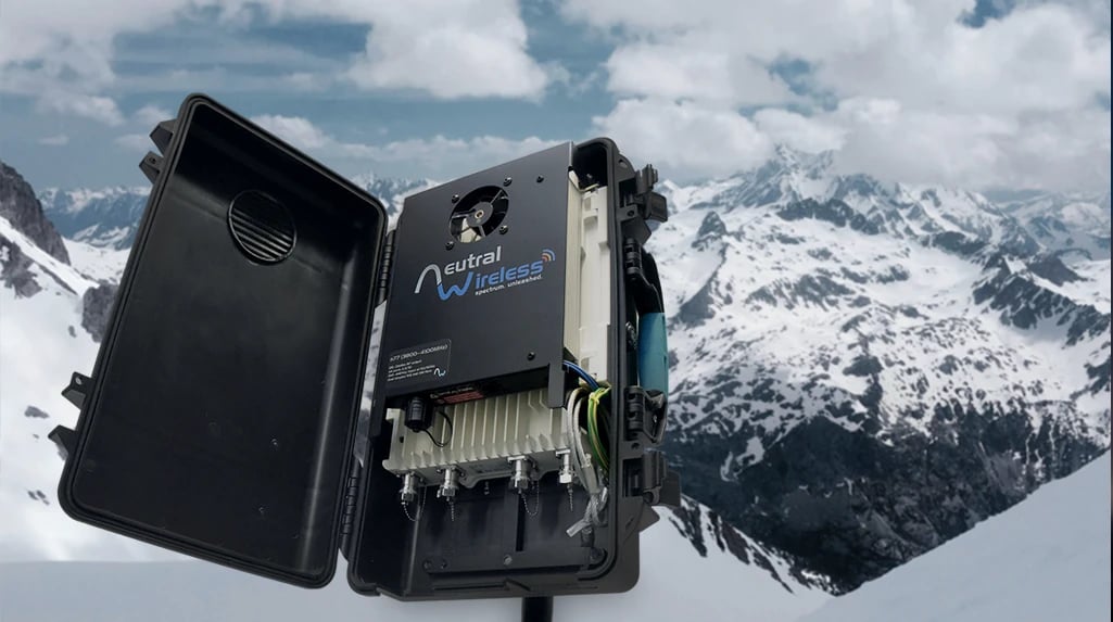 A wireless communication device in a black box, open on a snowy mountain landscape with cloudy skies.