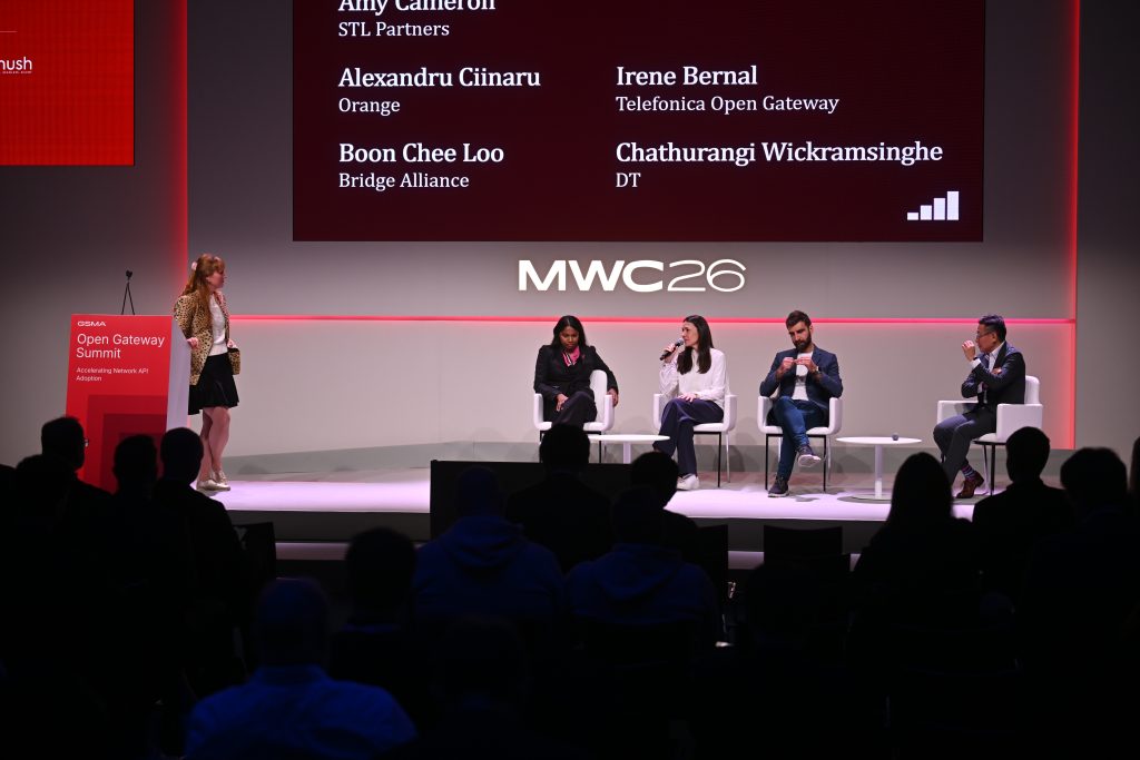 Five people on stage at an MWC 26 panel discuss api network monetisation and 5G operationalisation, with the audience seated in the foreground.
