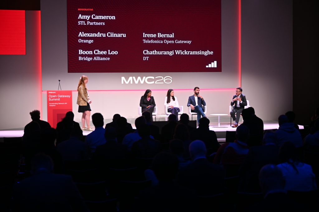 Five panelists sit on stage at MWC26, discussing 5G operationalisation and api network monetisation, with audience members seated in the foreground.