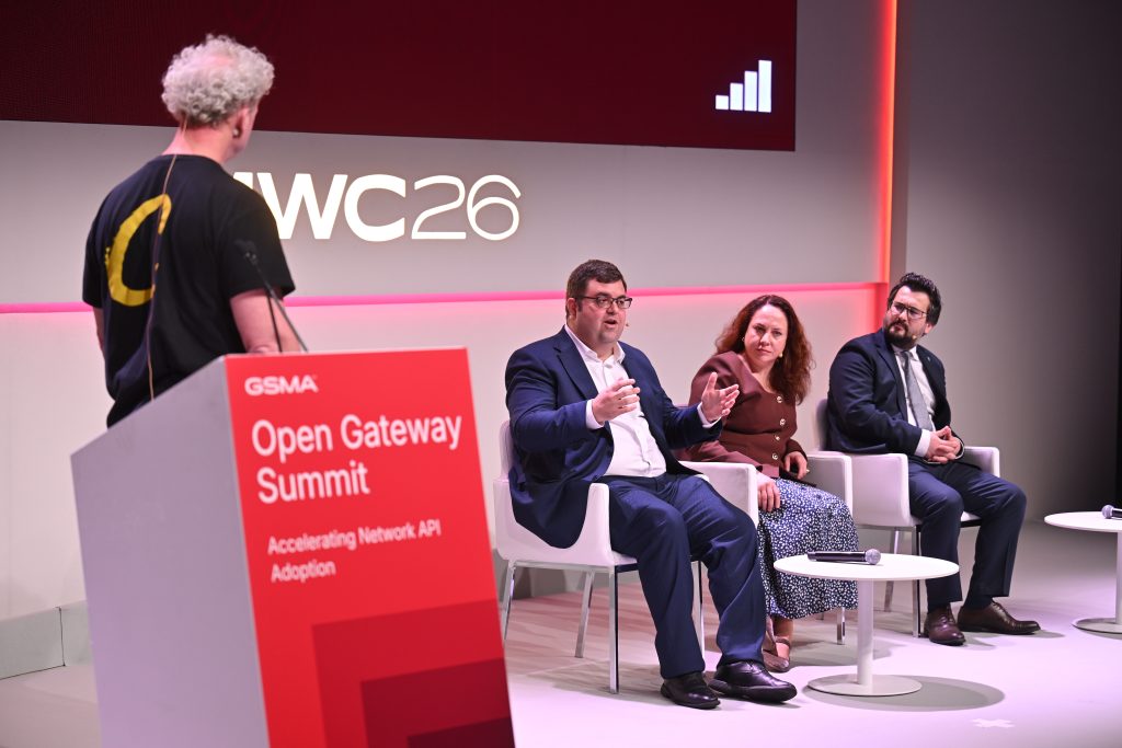 Three panelists discuss api network monetisation while seated onstage at the GSMA Open Gateway Summit; a moderator stands nearby.