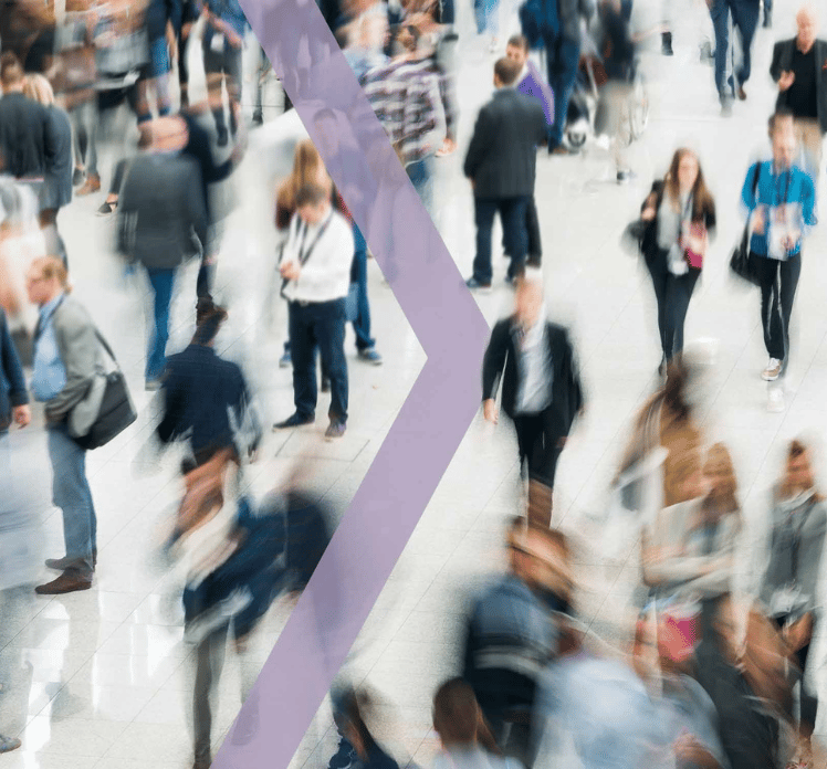 Blurred crowd of people walking indoors, with a large translucent purple arrow overlay pointing to the right.