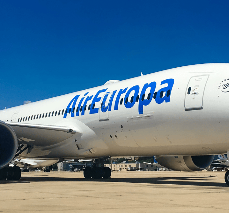 A white Air Europa airplane is parked on the tarmac under a clear blue sky.