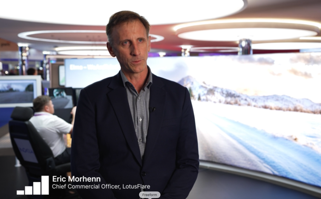 Eric Morhenn, Chief Commercial Officer at LotusFlare, speaks at a tech event with digital displays in the background.