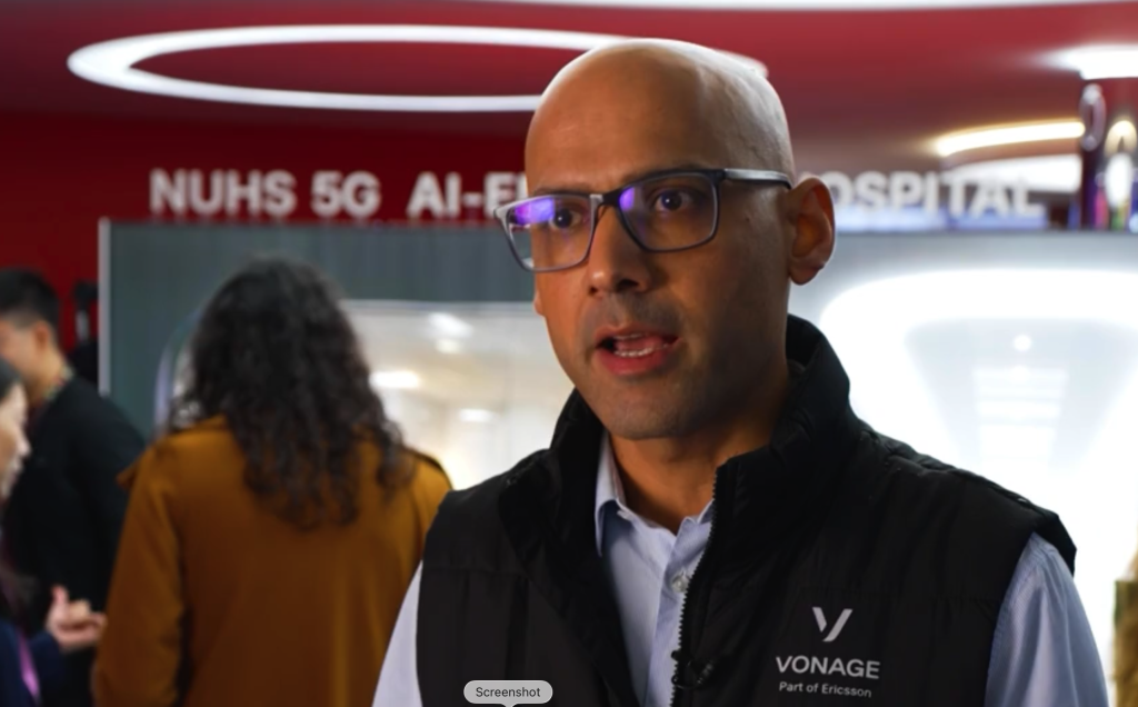A man in glasses and a Vonage vest speaks indoors; "NUHS 5G AI-FI" is visible in the background.
