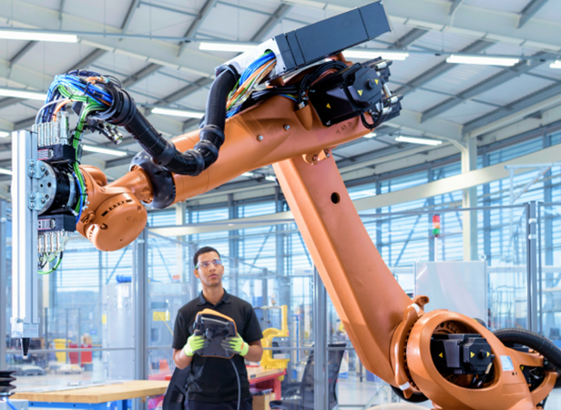 A worker is working with a robot in a factory.