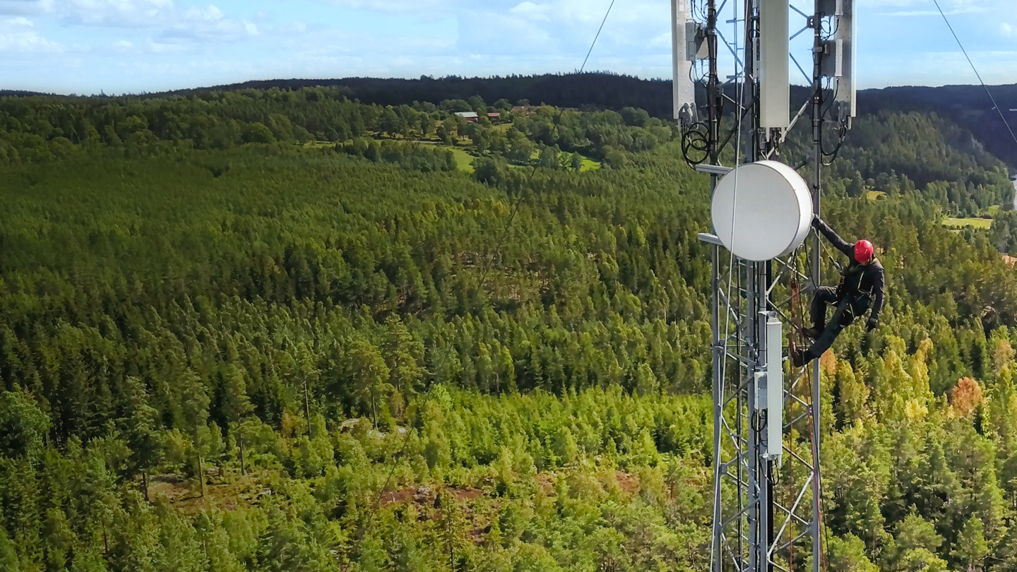 Telecommunication manual high worker engineer installing new 4g, 5g LTE antenna on tall mobile base station (communication tower) in the middle of forest. Working at height.