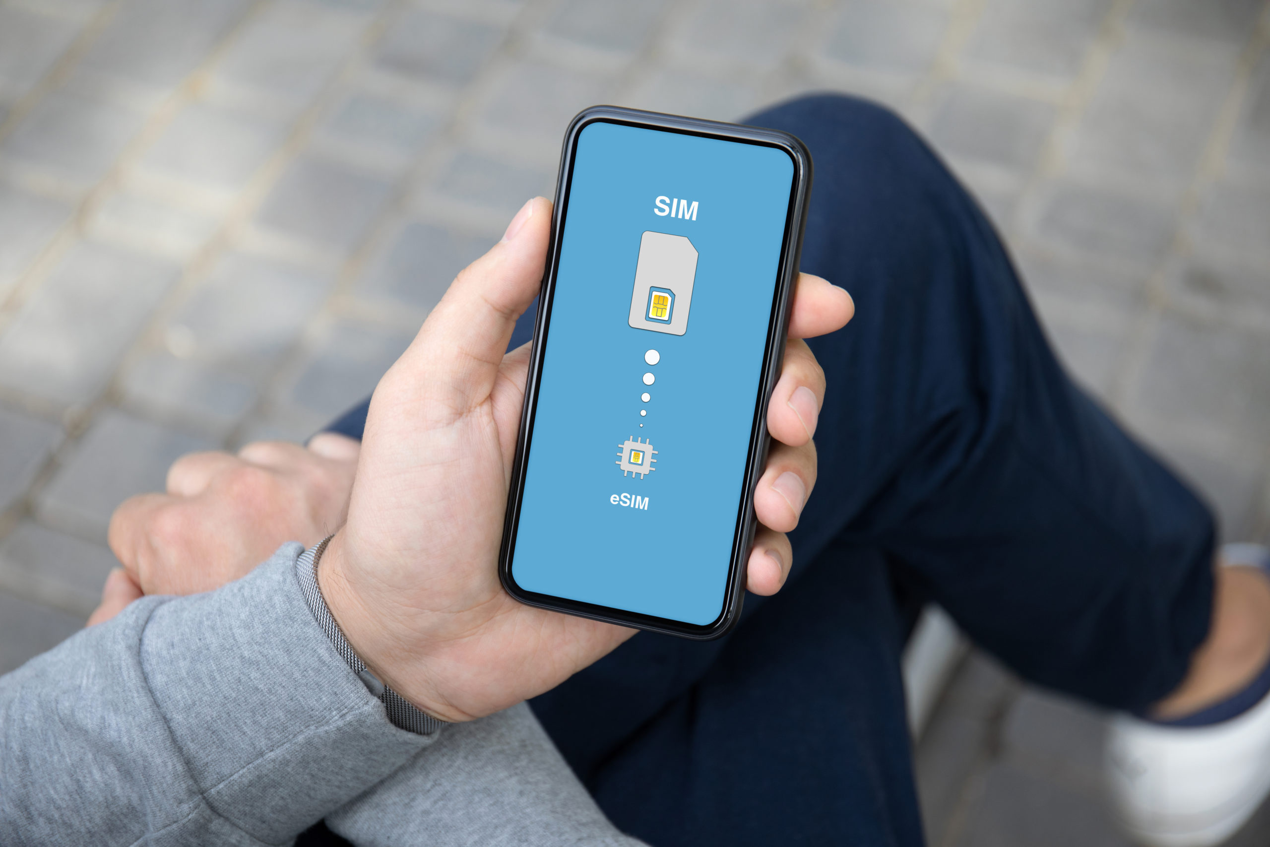 man hands on street holds phone with Sim card replacement on eSim