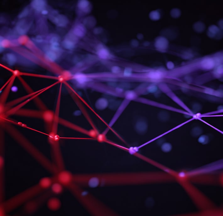 A digital illustration shows interconnected glowing nodes and lines forming a network against a dark background. Red nodes and lines are concentrated on the left, blending into purple on the right, creating an abstract, futuristic, and technological effect.