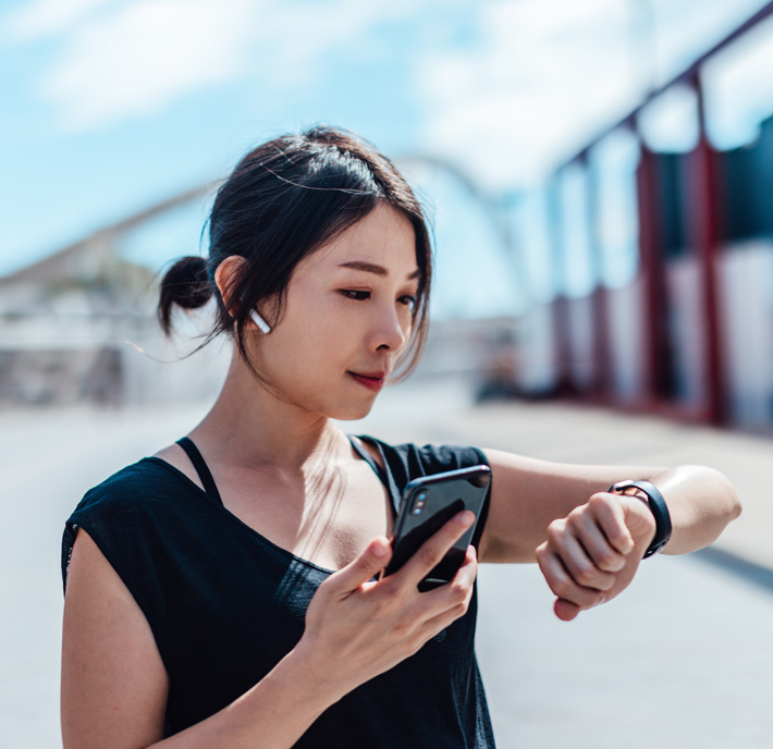 Woman holding mobile phone and looking at watch