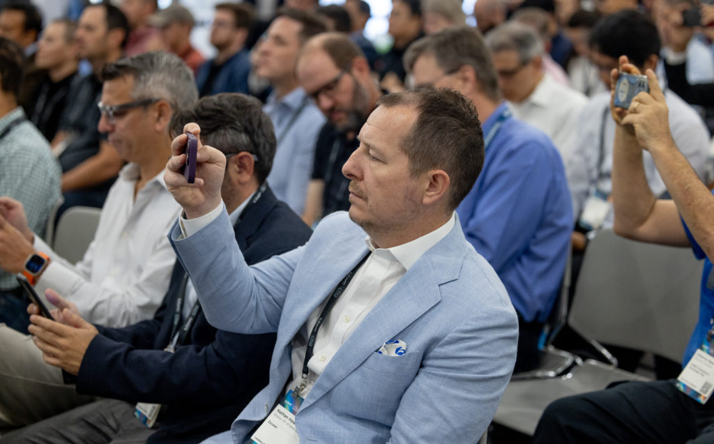 Someone in the audience taking a photo of the speaker on stage