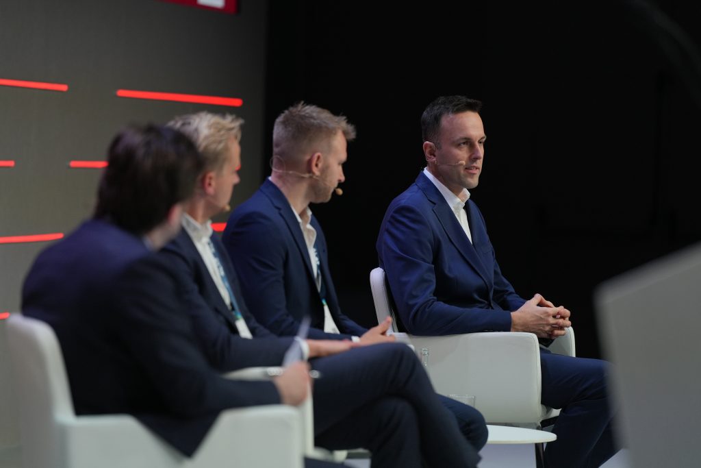 A closer image of the four men on stage talking