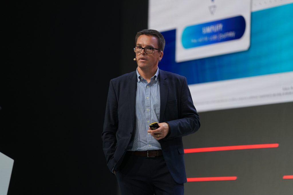 A closer image of the man on stage talking