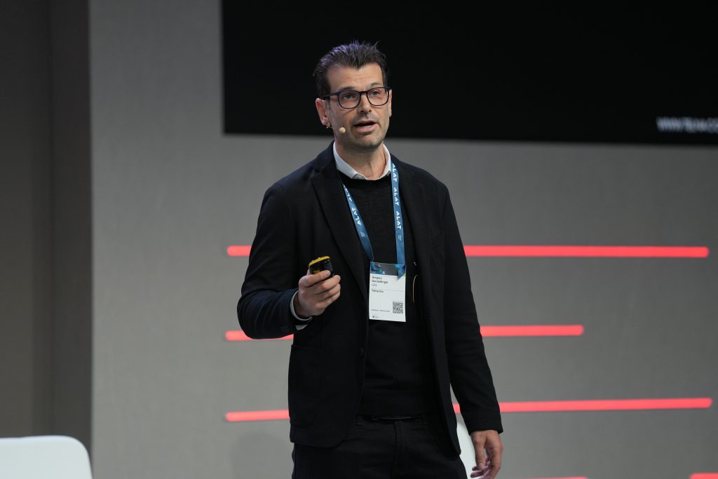 A closer image of the man on stage holding a device in his hand talking