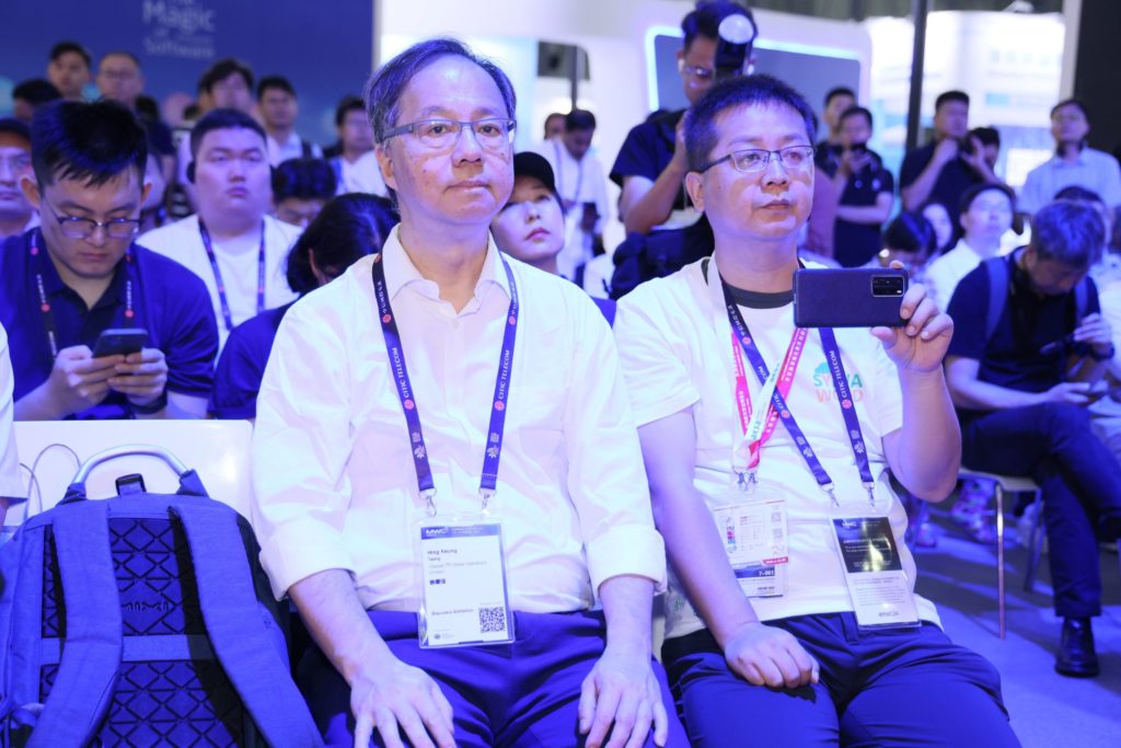 2 people sitting down with other people behind them