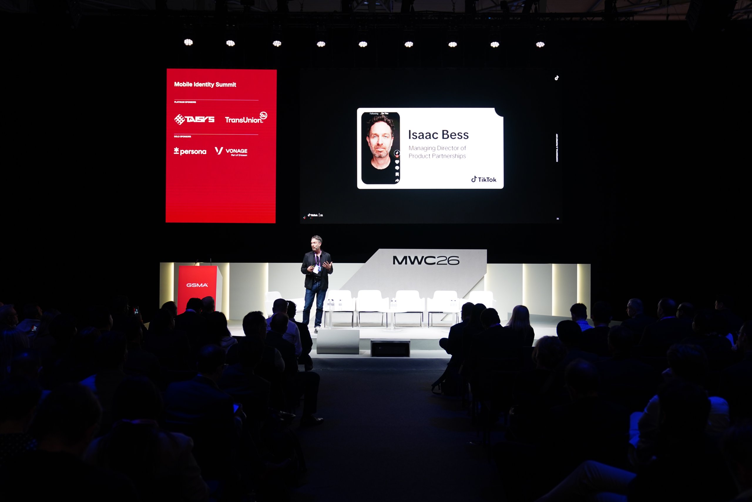 A speaker stands on stage at MWC26, presenting to an audience with a large screen behind him.