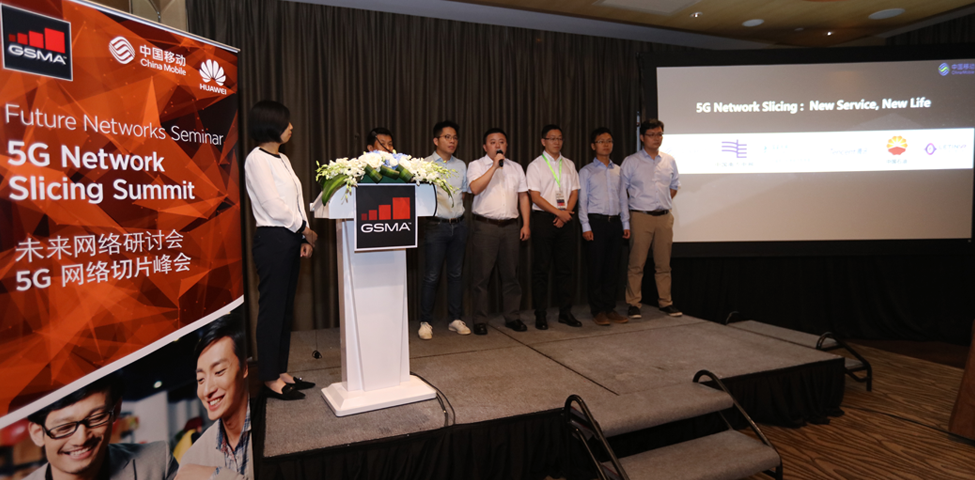 A group of people stands on a stage next to a podium with a bouquet, presenting at the 5G Network Slicing Summit. A large screen displays the title "5G Network Slicing: New Service, New Life." A banner with logos and Chinese text is on the left.