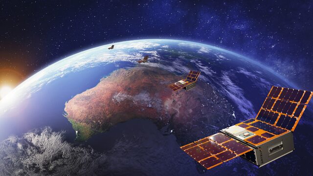 Four small cube-shaped satellites with solar panels orbit above Earth, which shows a sunlit Australia. The satellites are floating in space with a backdrop of the planet’s curved horizon, deep blue oceans, and the sunrise at the edge of the scene.