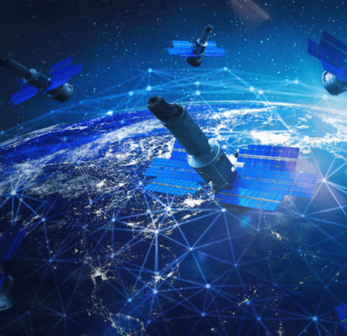 Several satellites with blue solar panels orbit above Earth, connected by glowing network lines. The planet below is illuminated, showing continents, city lights, and a digital grid overlay, symbolizing global connectivity and communication.