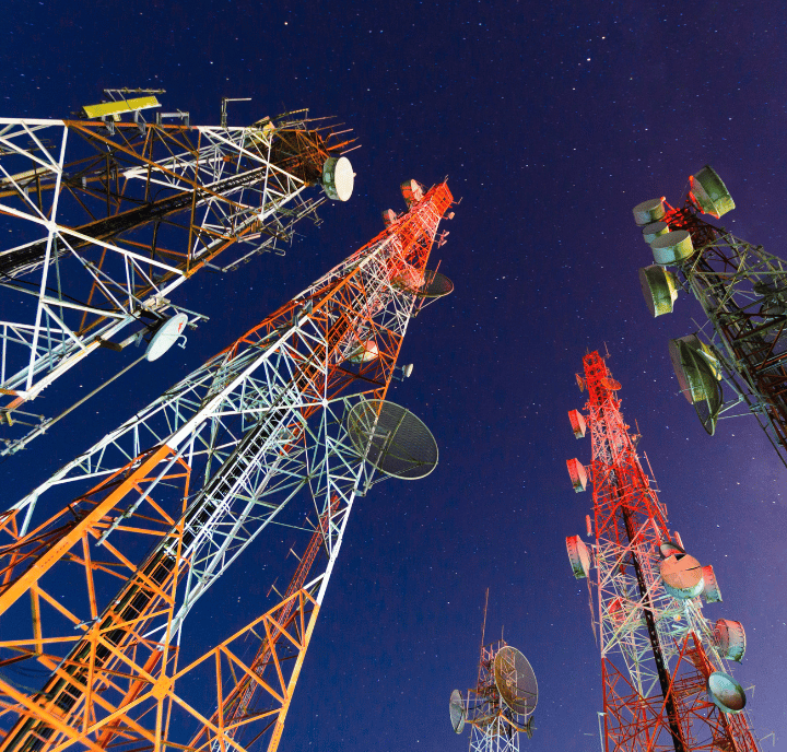 Several tall, red and white communication masts with aerials, part of GSMA networks, stand against a clear, starry night sky.