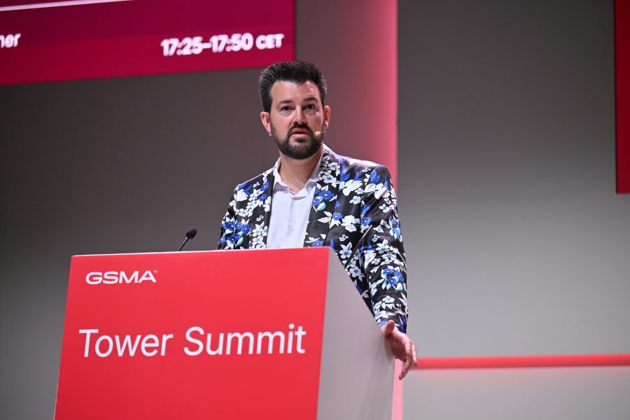 A man in a floral jacket speaks at a lectern labelled "GSMA Tower Summit.