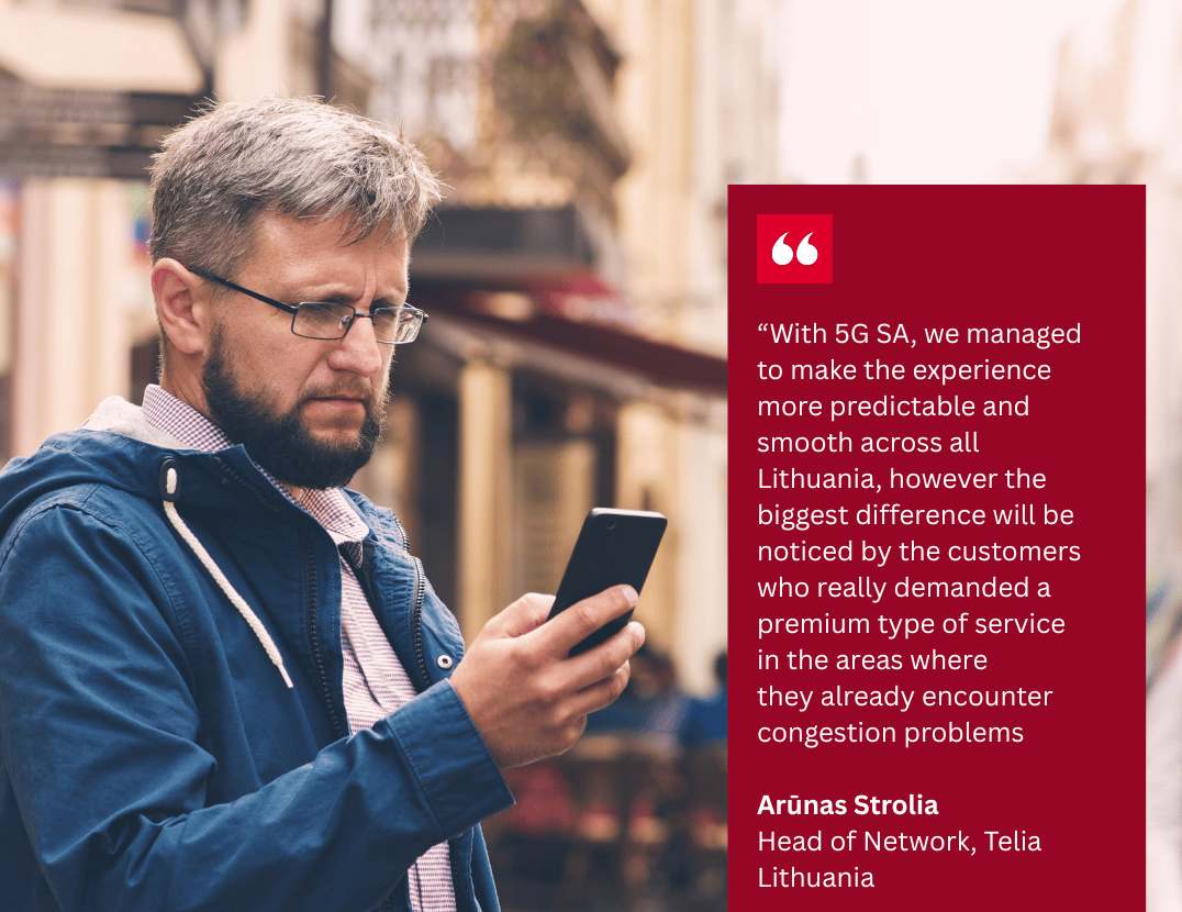 A man with glasses and a beard, wearing a blue jacket over a red shirt, looks at his mobile phone on a city street. Next to him is a red box with a quotation about 5G SA from Arūnas Strolia, Head of Network at Telia Lithuania.