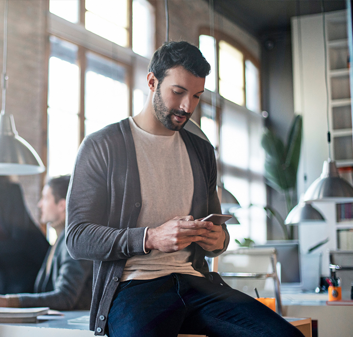 Man sat on desk using his mobile device.