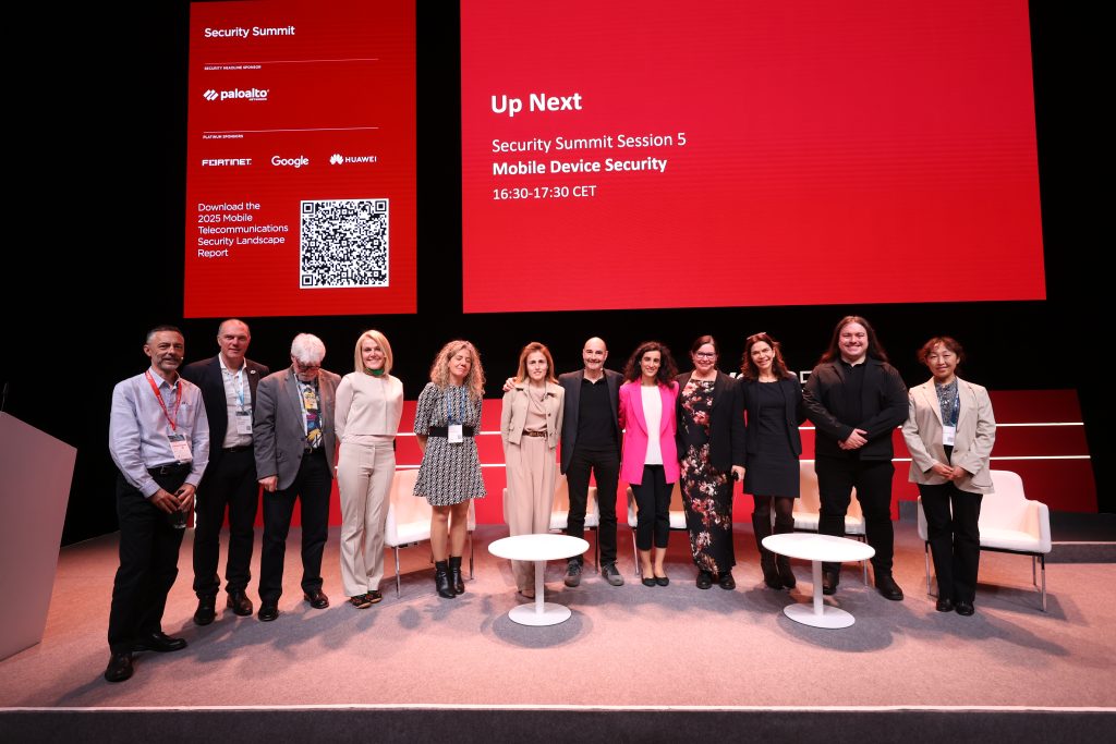 A group of eleven people stand on a stage in front of a red screen displaying "Up Next Security Summit Session 5 Mobile Device Security 16:30-17:30 CET." With post-quantum security as an urgent challenge for the mobile industry, logos and a QR code adorn the backdrop behind white chairs.
