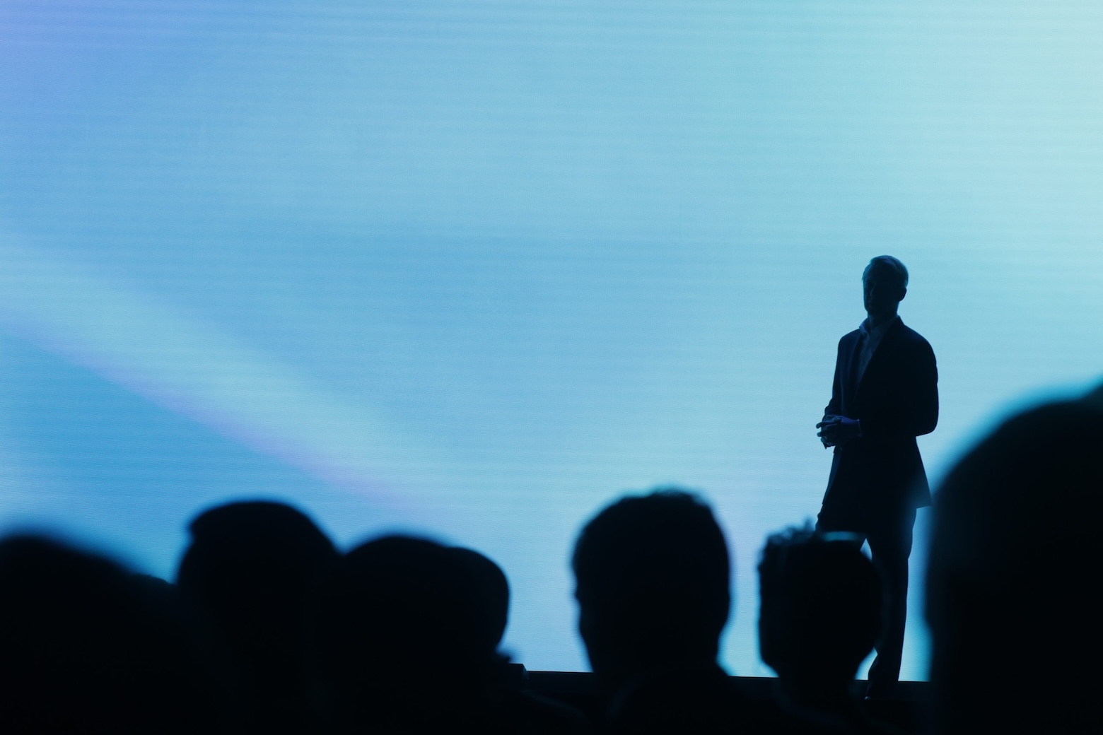 A person in a suit is standing in front of a large screen.