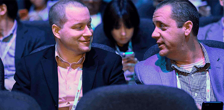 Two men sitting next to each other at a conference.