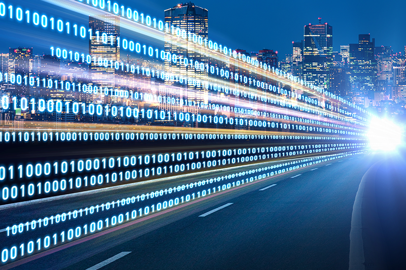 An image of a city at night with binary code on the road.
