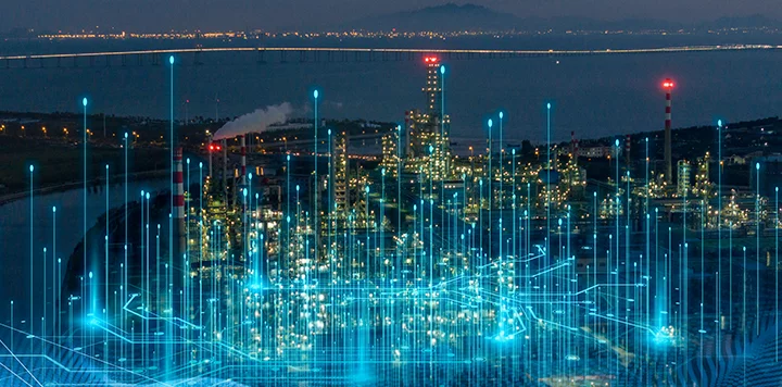 A nighttime view of an illuminated industrial complex with smokestacks. Blue digital lines and glowing data points overlay the image, suggesting technology, connectivity, and digital transformation in the industrial sector. Mountains and a bridge appear in the background.