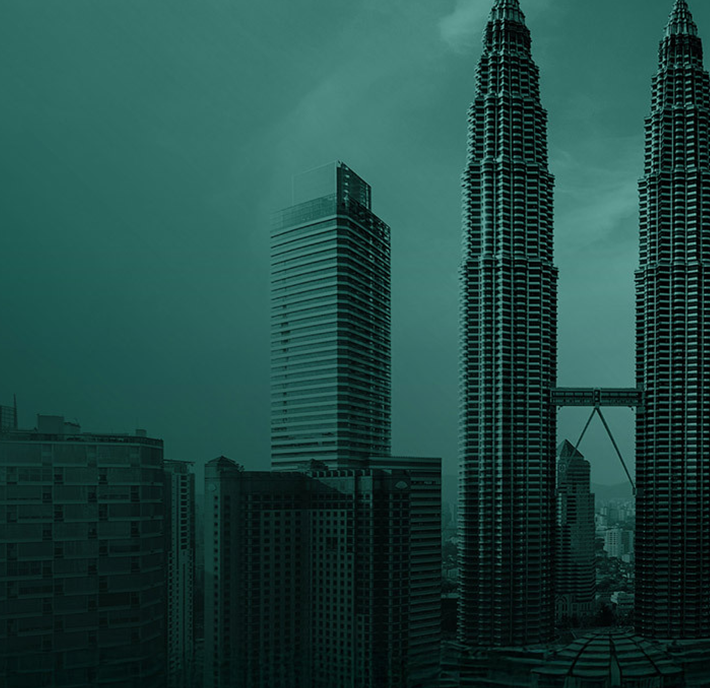 A misty cityscape featuring the tall, twin Petronas Towers with their skybridge in Kuala Lumpur, Malaysia. Modern high-rise buildings surround the towers, and the overall image has a teal color tone.