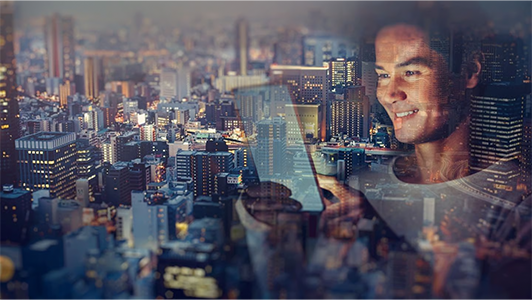 A smiling person looks at a tablet in the evening, superimposed over a brightly lit city skyline with many tall buildings and glowing windows, creating a visually blended image of technology and urban life.